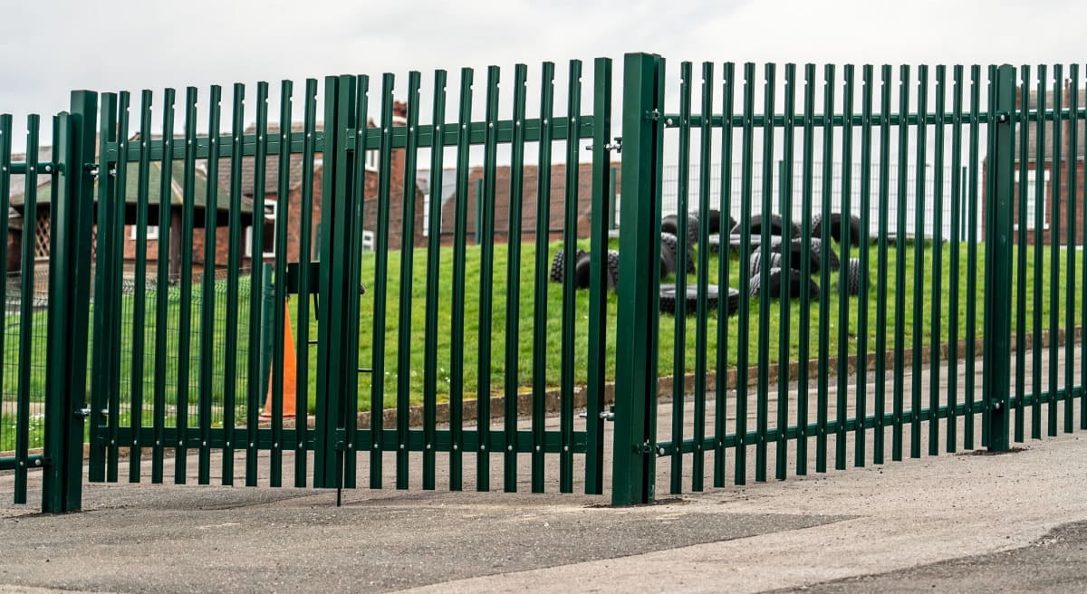 Green Round Top Palisade Fencing and Gate Around a School Playing Field 