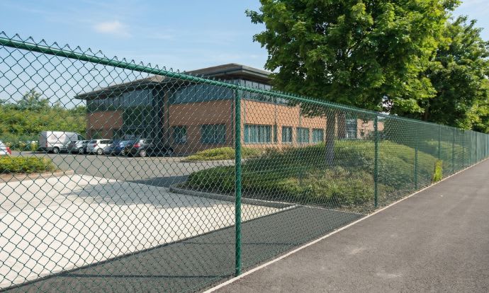 Green chain link fencing installed outside an office building