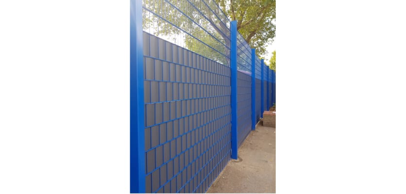 Grey privacy fencing rolls installed on blue mesh fencing 