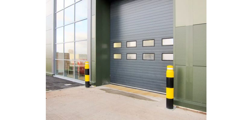 Two yellow and black bollards protecting a warehouse door