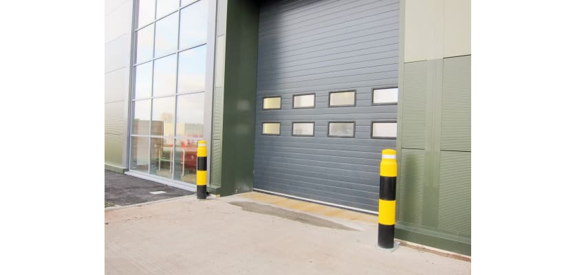 Two bollards with yellow and black covers protecting a warehouse door