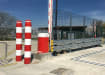 Red and White polymer cover kit on two steel bollards next to a raise arm barrier