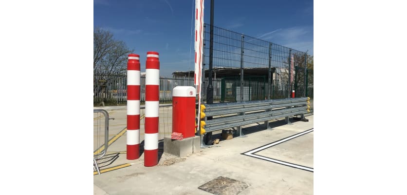 Two Red and White bollards next to a raise arm barrier