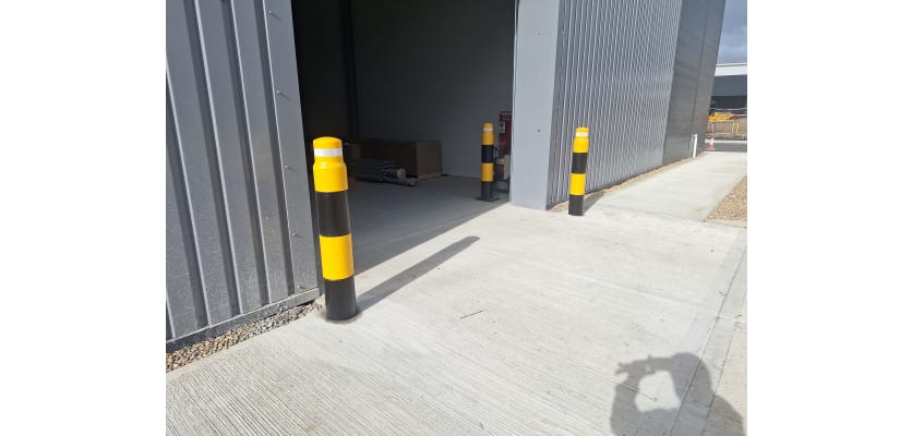 Black and yellow potted bollards outside a warehouse door