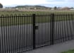 A Black Single Leaf EnviroRail® PlaySec Railing Gate securing a park 