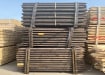 Creosoted timber posts stacked in bundle for storage
