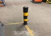 Plain yellow and black bollard installed inside a warehouse