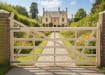 A ranch gate on a stone pathway, leading to a house