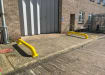 Two Yellow Galvanised Steel Wheel Guides Bolt Down outside warehouse