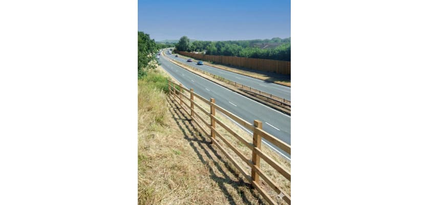 Post and rail fencing installed next to highway