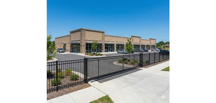 Aluminum Rackable Commercial 3-Rail Flat Top Fence Panels installed around a commercial parking lot yard.