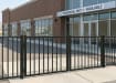 A black, 2-rail flat top commercial driveway gate pair installed at the entrance of a commercial unit to manage vehicle access.