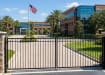 Black Aluminum Commercial Driveway Gate pair with a 3-rail staggered spear design and a safe flat top rail, installed at a school entrance to provide secure access.