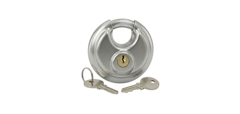 Silver round circular padlock with two silver keys laying on a white surface.